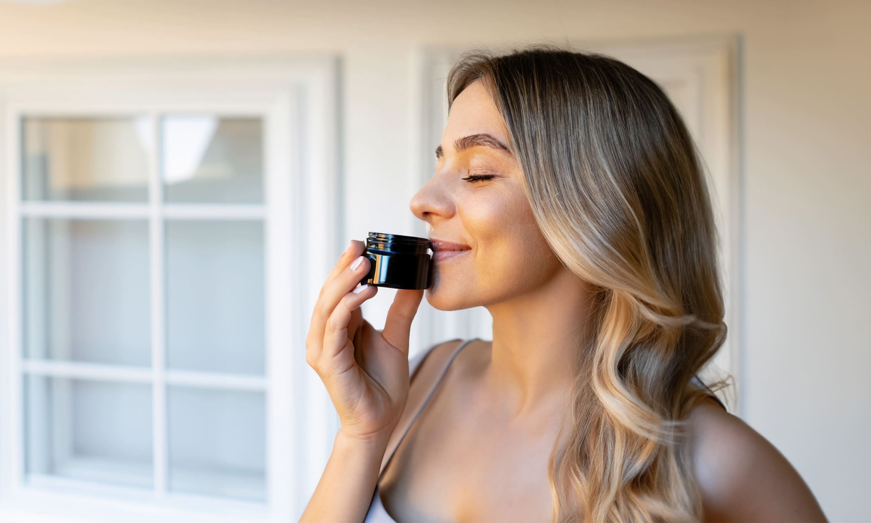 Blonde Frau riecht an einem Riechglas eines Riechtrainings