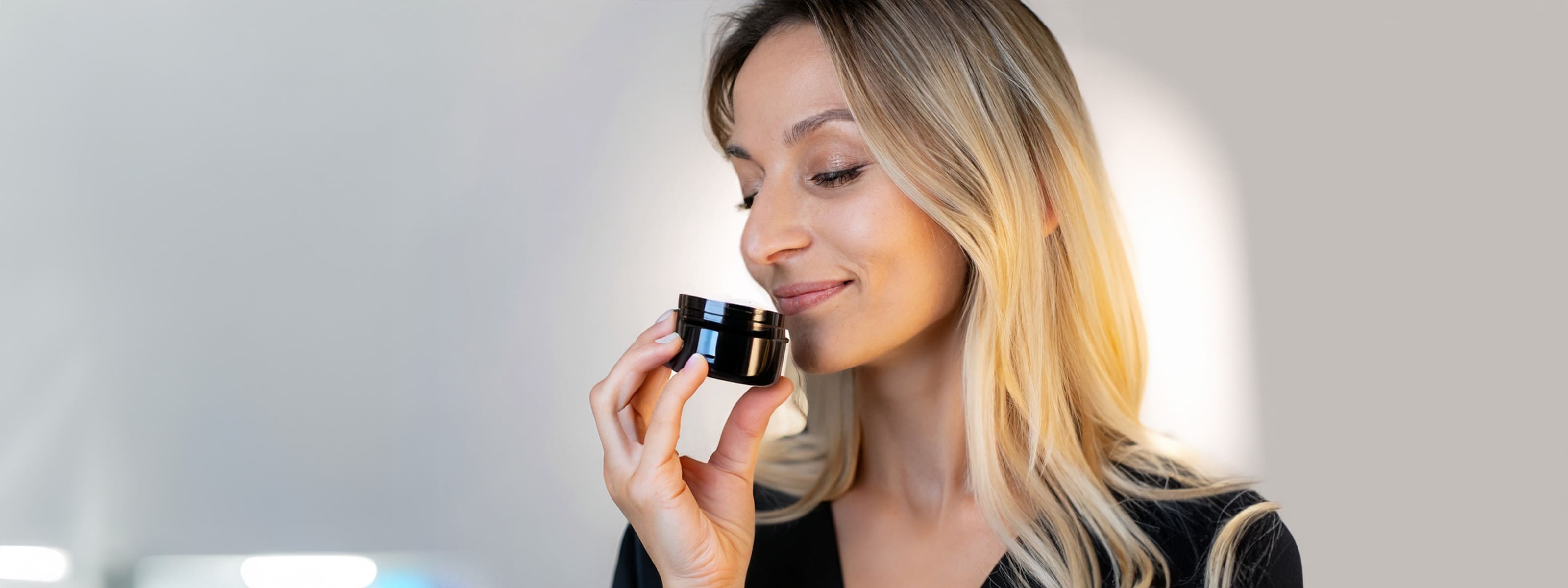 Blonde Frau riecht an schwarzen Riechglas eines Riechtrainings